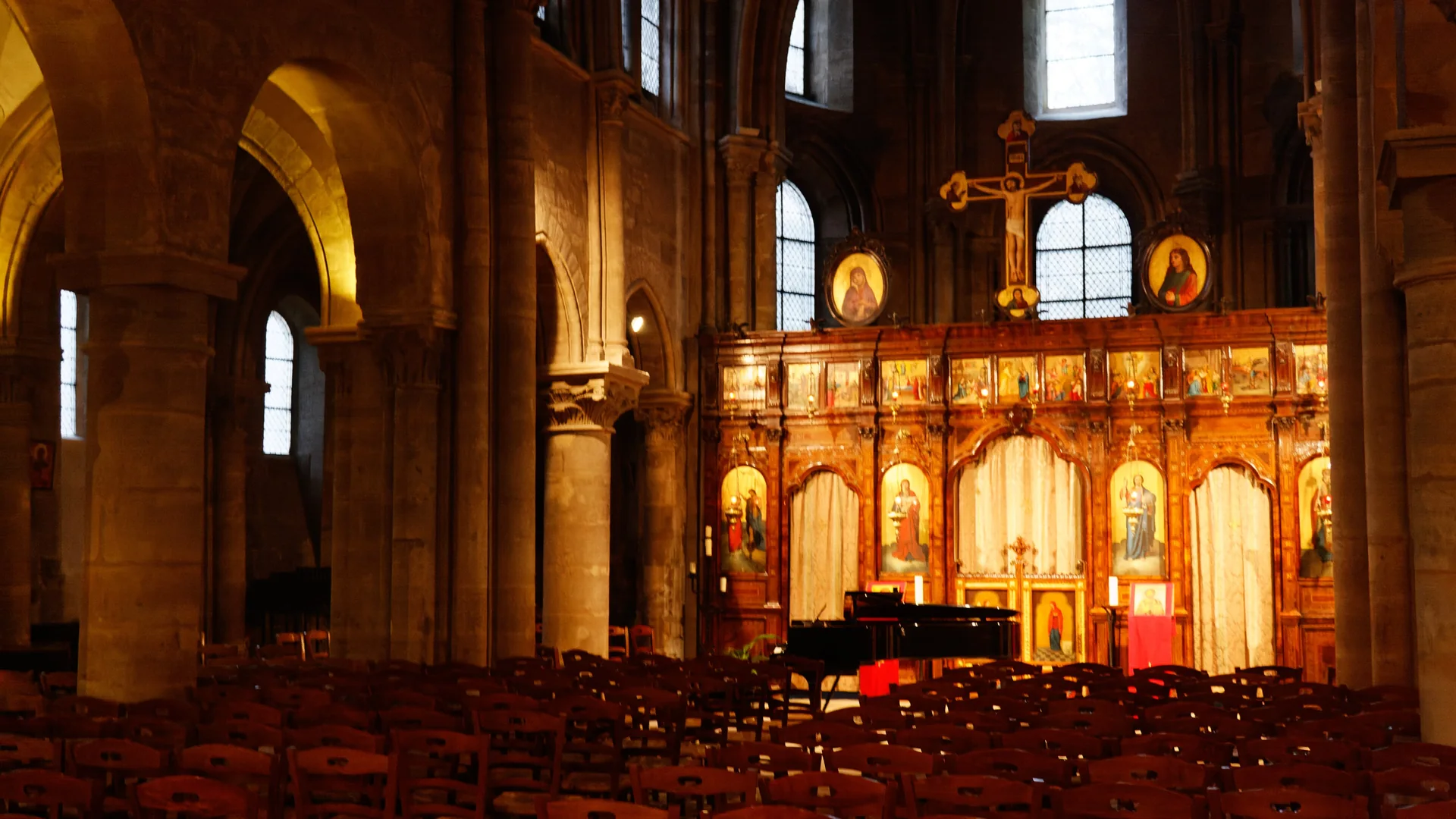 Rows of wooden chairs and a grand piano in front of the gilded, icon-covered iconostasis inside the church of Saint-Julien-le-Pauvre in Paris