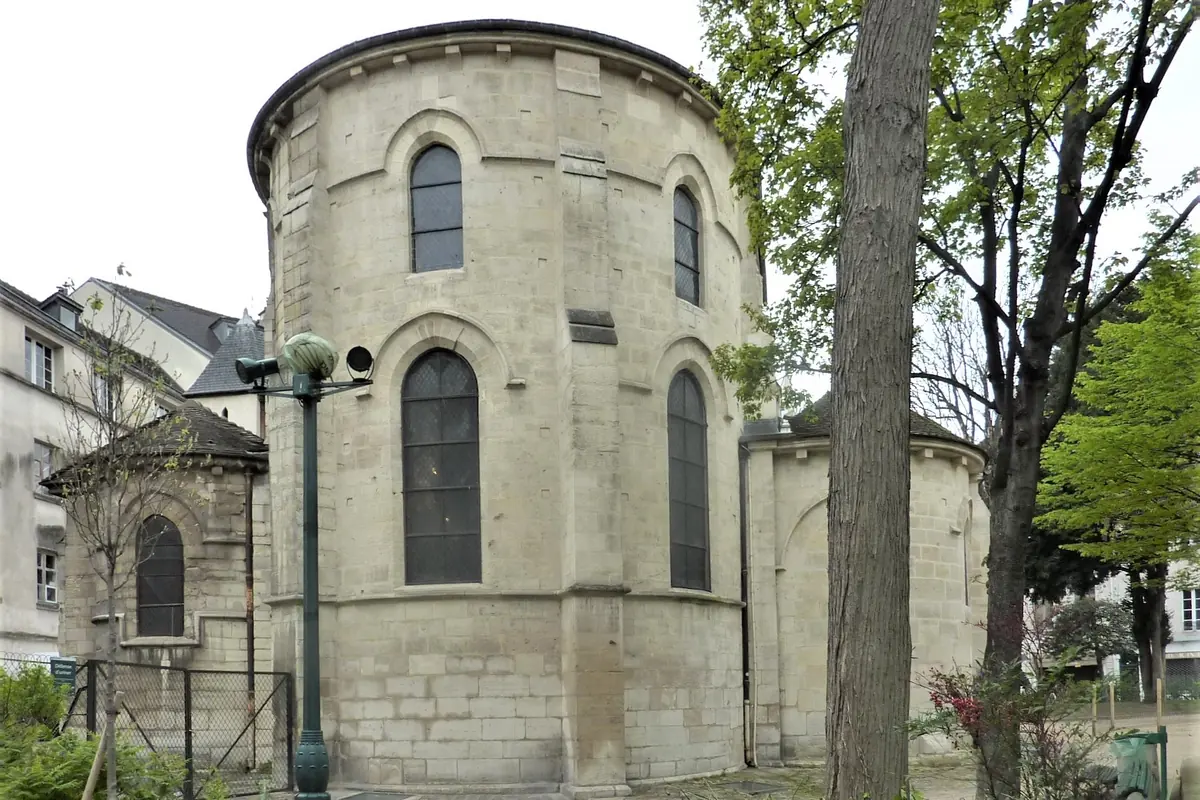The rounded stone east end of Saint-Julien-le-Pauvre with tall arched windows, framed by trees.