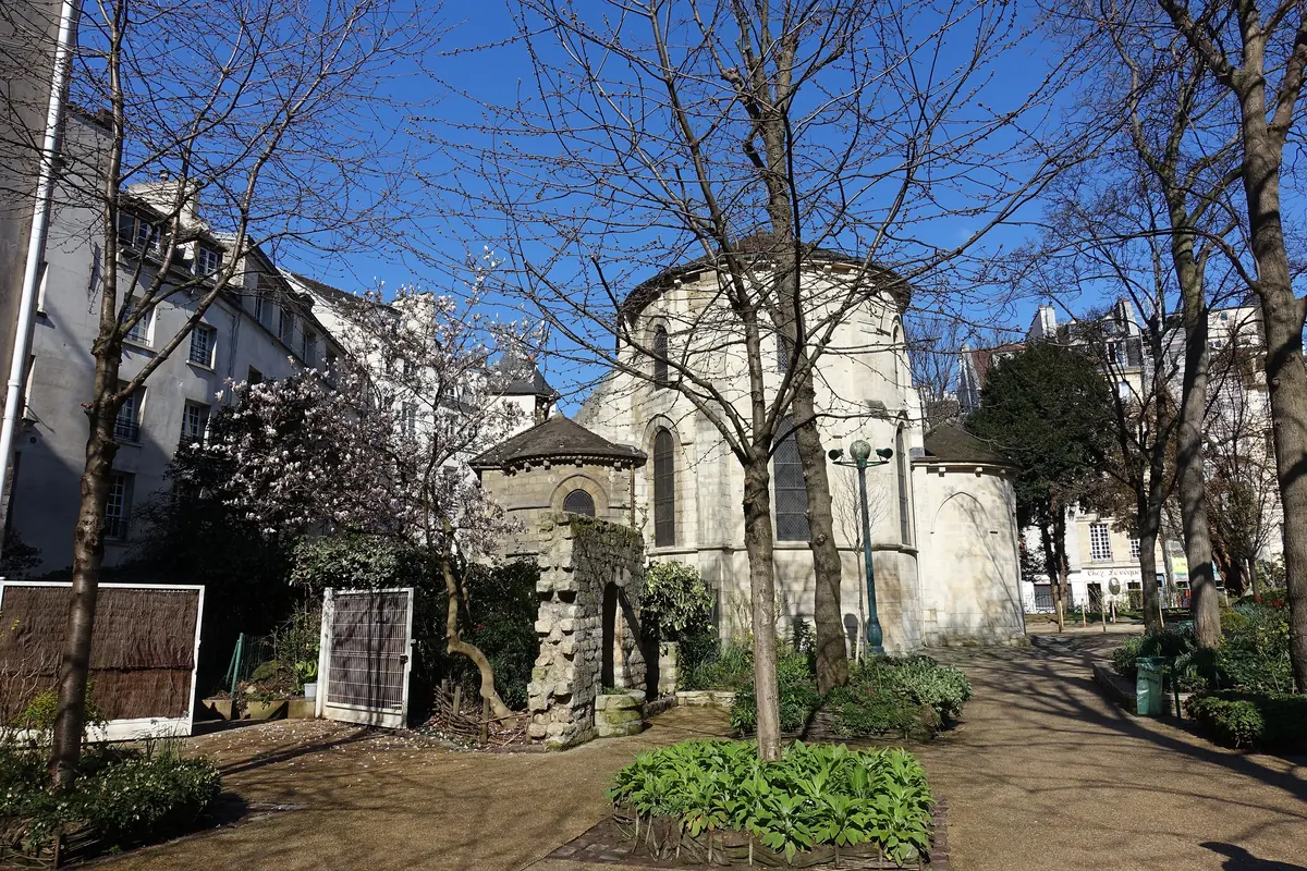 Square René-Viviani in early spring with bare trees, a white blossoming tree and the rounded east end of the church.